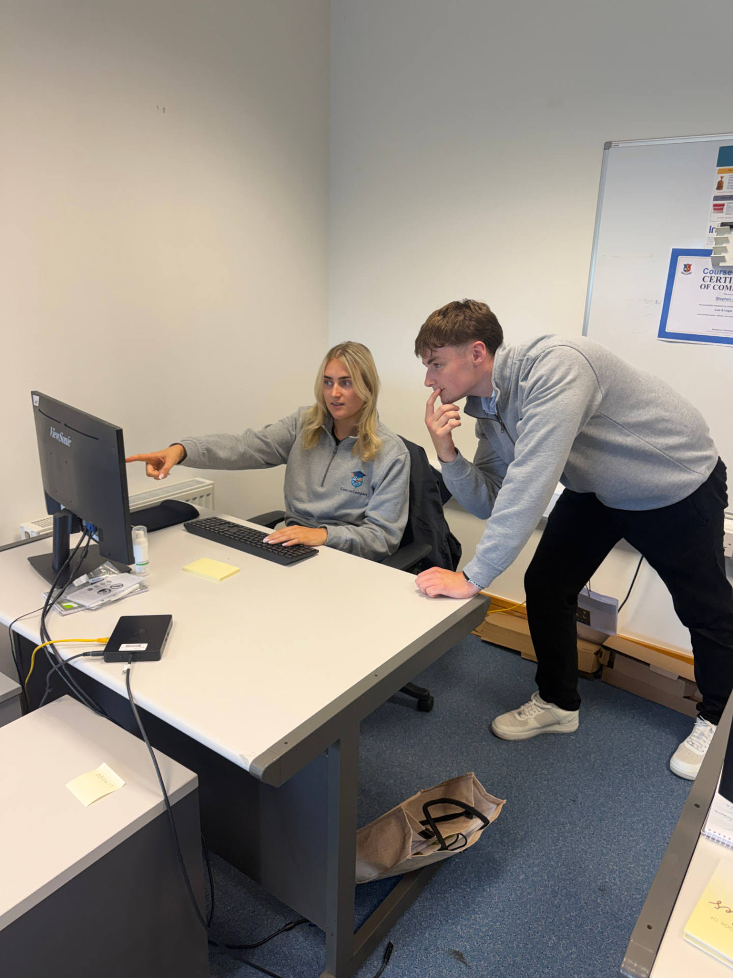 CourseCompass team members reviewing a student dashboard on a monitor